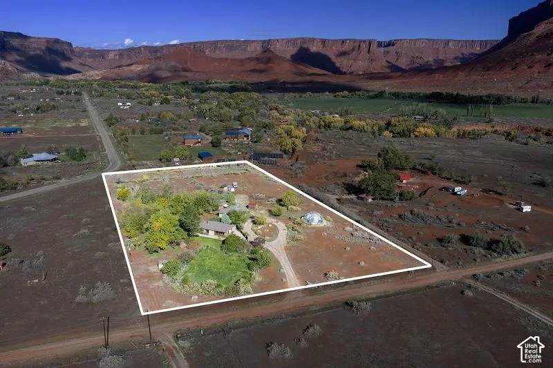 Expansive property featuring mature trees, a detached dome structure, winding gravel driveway, and prominent mesa rock formations