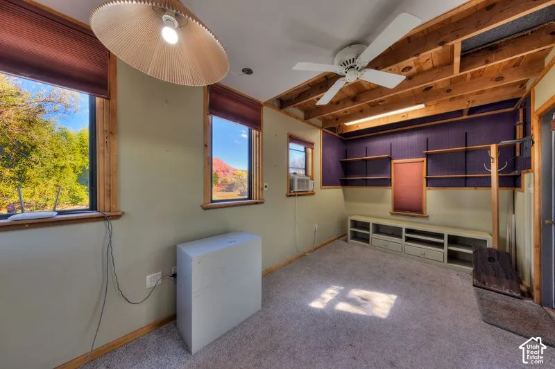 Exposed wood ceiling beams, built-in shelving, integrated lower cabinetry, recessed lighting, and large windows with natural scenery