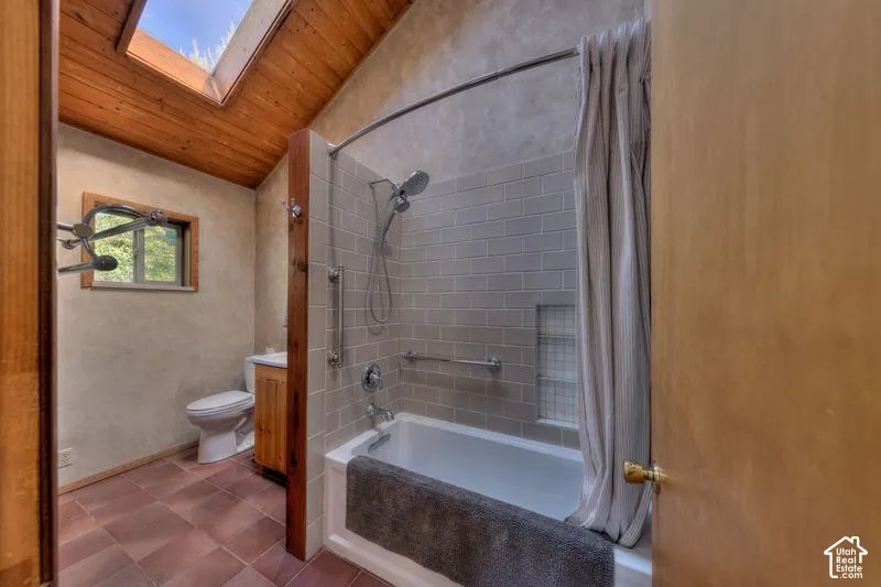 Bathroom featuring a wood-plank vaulted ceiling with a skylight, subway-tiled shower surround with a built-in recessed niche, ceramic tile flooring, and a wood-finish vanity