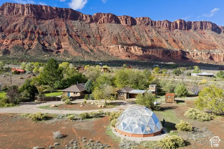 Expansive lot featuring a geodesic dome structure, mature vegetation, and a prominent red rock mountain backdrop
