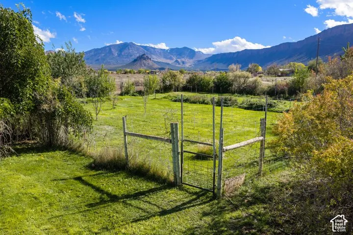 Expansive lot featuring a fenced garden area, mature trees, and prominent mountain scenery