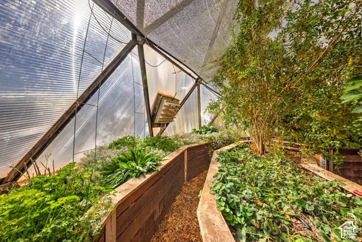 Geodesic-style greenhouse featuring a structural metal frame, translucent polycarbonate panels, a mechanical ventilation system, and tiered raised garden beds constructed from wood