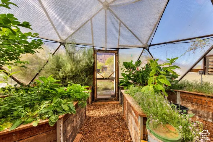 Geodesic greenhouse featuring a translucent panel structure, wood-framed raised garden beds, and a wood-chip ground surface
