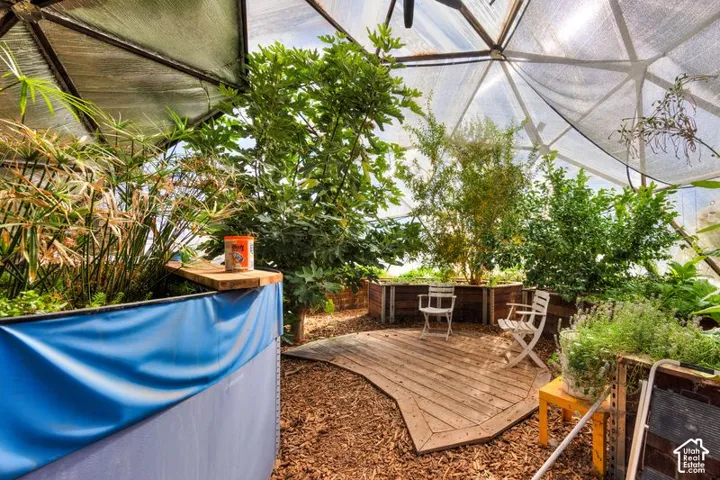 Geodesic dome greenhouse featuring a metal frame, translucent roof panels, a wood-plank deck, and raised garden planters