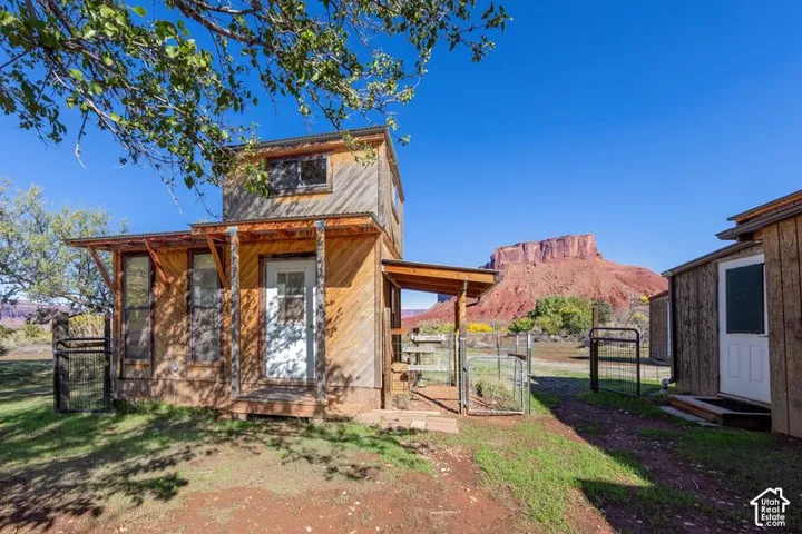Multi-level structure with diagonal wood-plank siding, metal roof accents, covered entrance porch, and scenic mesa backdrop