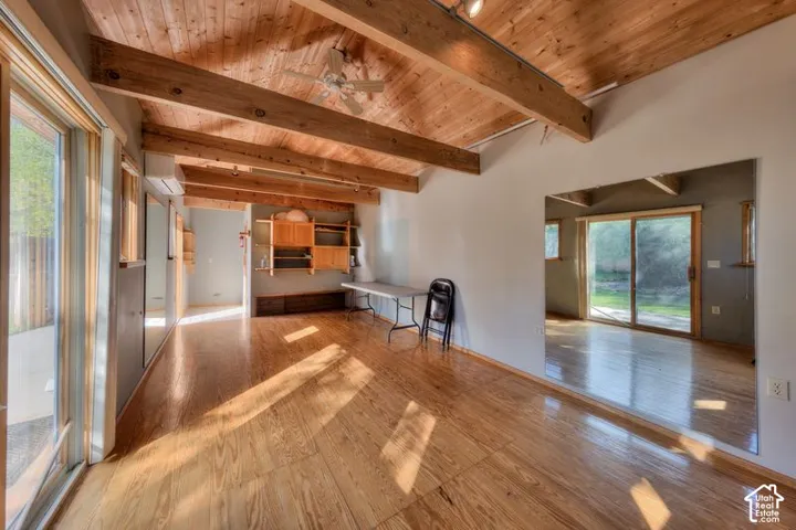 Studio with exposed timber ceiling beams, wood-finish flooring, full-wall mirrors, built-in wooden shelving, and sliding glass doors