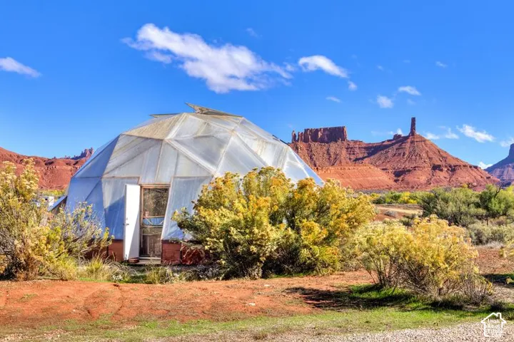 Geodesic dome structure featuring translucent paneling and a dedicated entryway, set against a backdrop of prominent rock formations