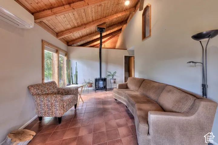 Vaulted wood-plank ceiling with exposed timber beams, ceramic tile flooring, and a free-standing metal stove