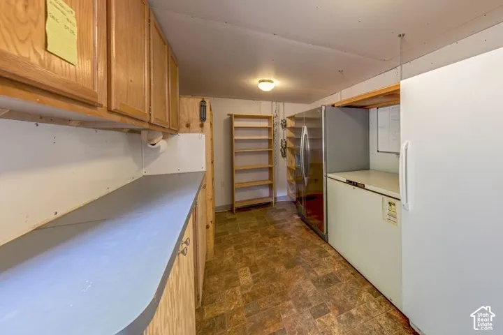 Pantry  featuring wood cabinetry, countertop surface, built-in shelving units, and vinyl flooring