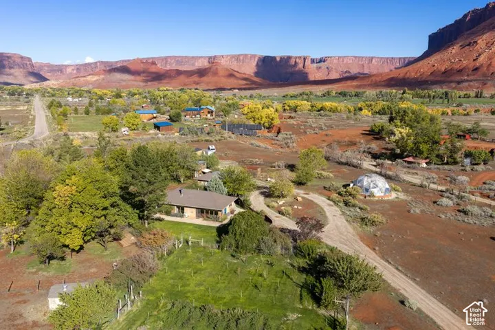 Aerial perspective of expansive grounds featuring mature trees, a manicured lawn area, a geodetic dome structure, and dramatic red rock canyon backdrops
