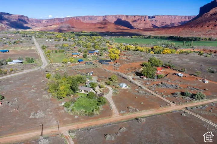 Aerial perspective featuring desert terrain, mature vegetation, a paved driveway, and rock formation scenery