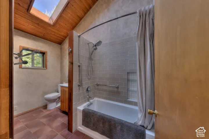 Bathroom featuring a wood-plank vaulted ceiling with a skylight, subway-tiled shower surround with a built-in recessed niche, ceramic tile flooring, and a wood-finish vanity
