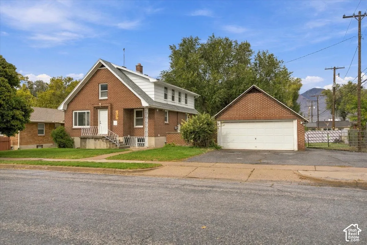 Brick exterior residence with a multi-level roofline, gabled entrance, detached two-car garage, and concrete staircase