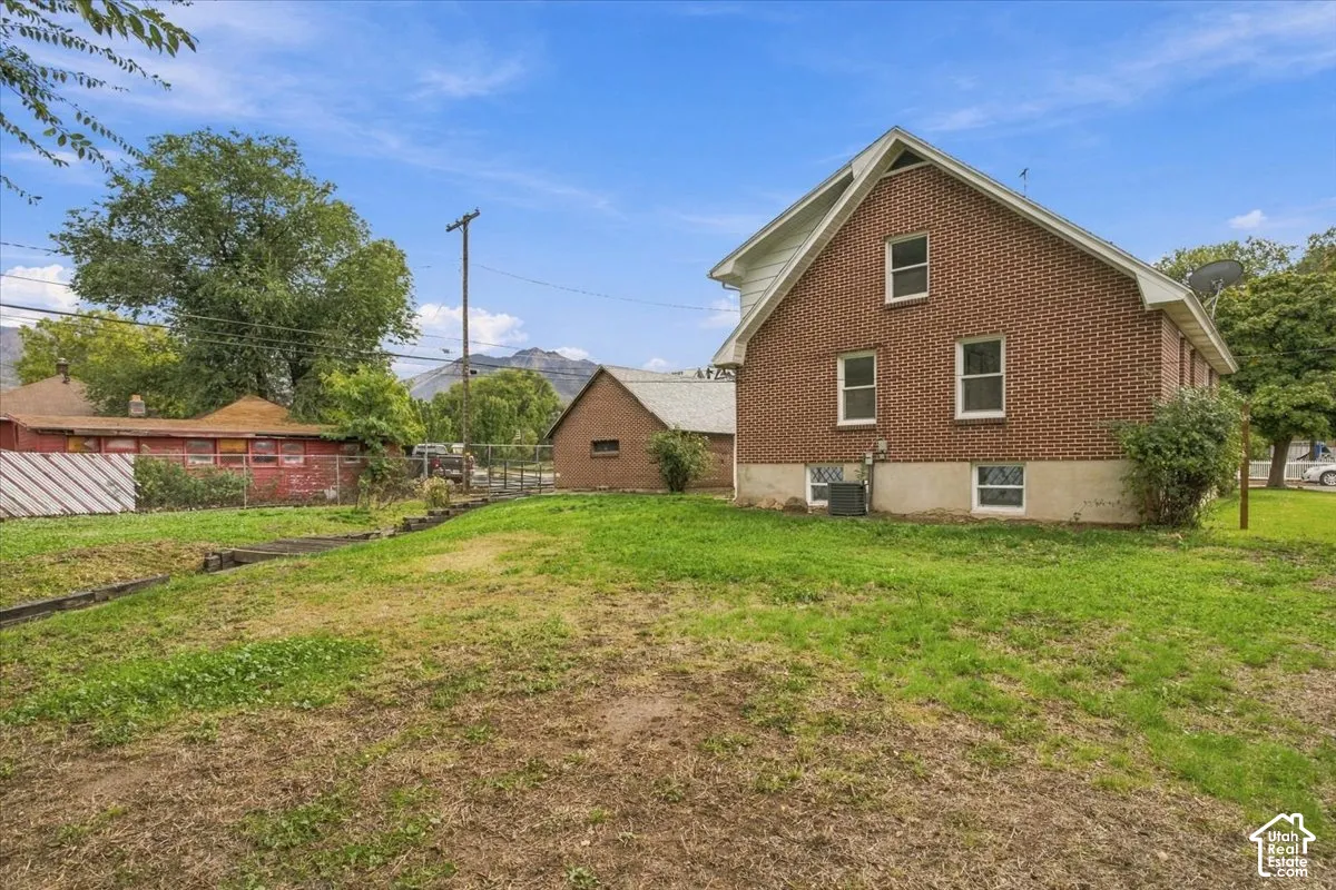 Brick exterior siding, detached garage structure, concrete foundation, and mountain backdrop