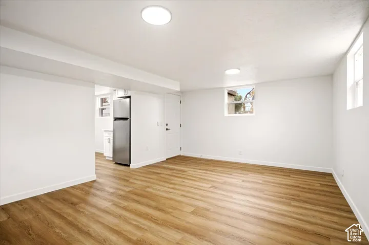 Open interior space featuring wood-finish flooring, neutral white walls, recessed ceiling lighting, and exterior-facing windows