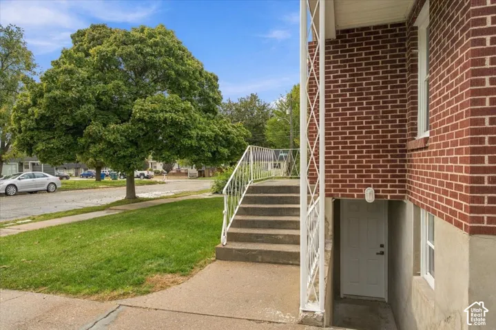 Exterior featuring red brick masonry, concrete stairs with white metal railings, and a lower-level entryway