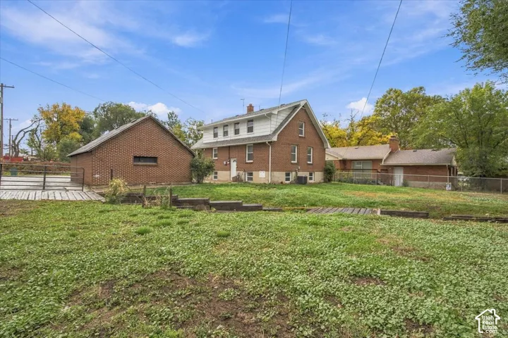 Expansive backyard featuring a tiered lawn, detached brick garage, brick exterior, and a chain-link fence