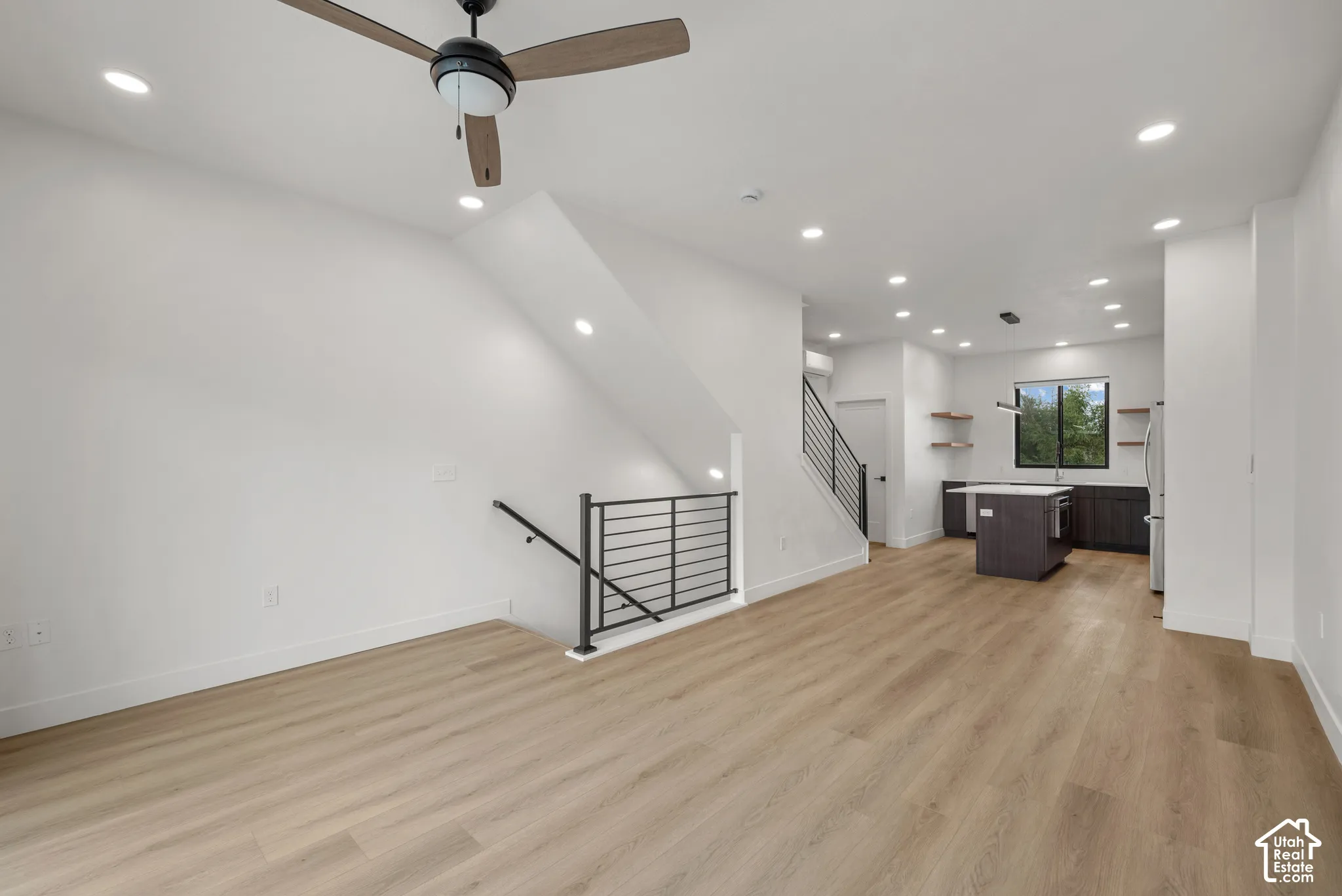 Open-concept interior featuring wood-finish flooring, recessed lighting, a ceiling fan, and metal stair railings