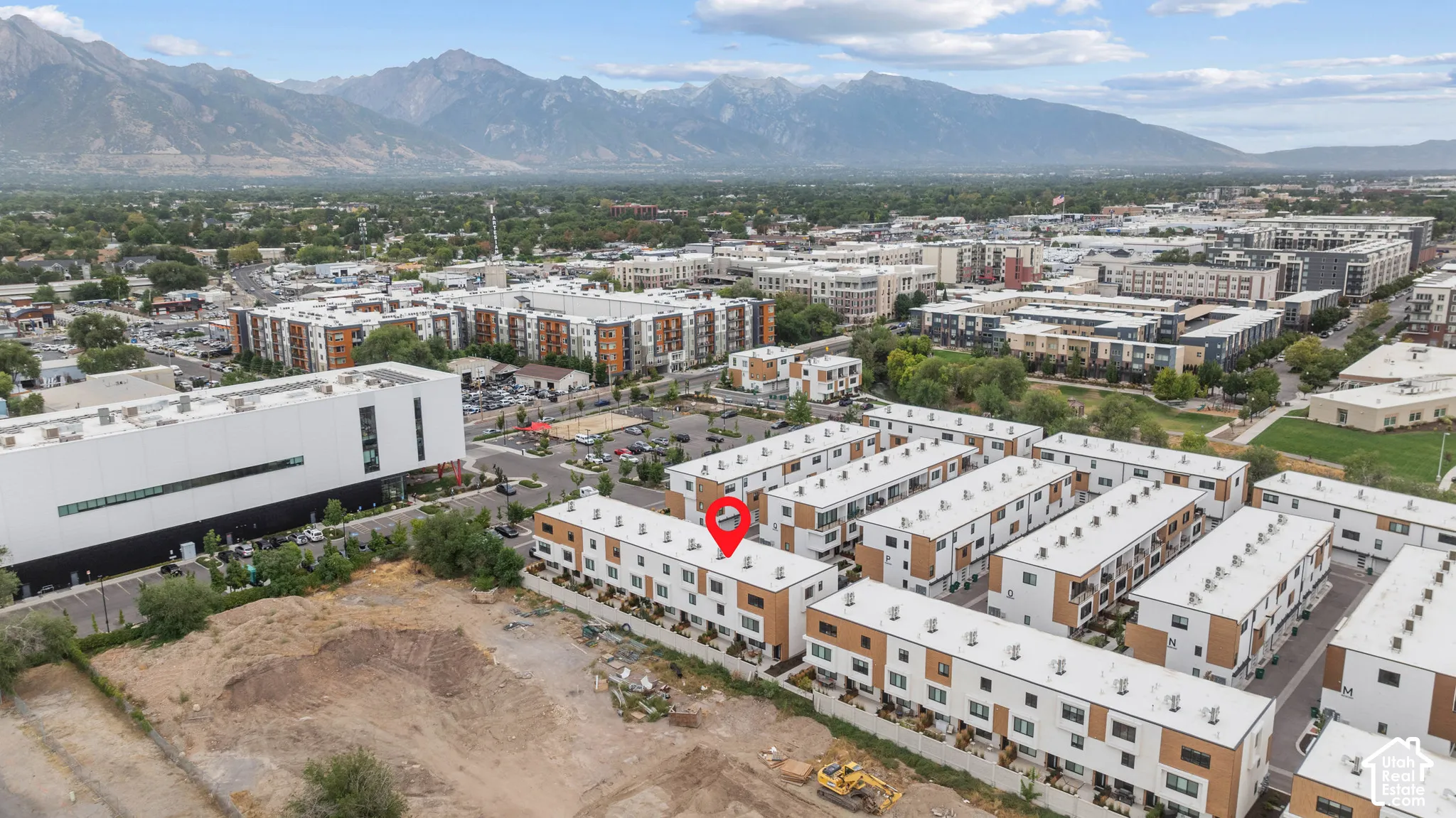Aerial perspective of multi-story residential structures featuring contemporary flat-roof architecture, wood-tone and white exterior paneling, and a prominent mountain backdrop