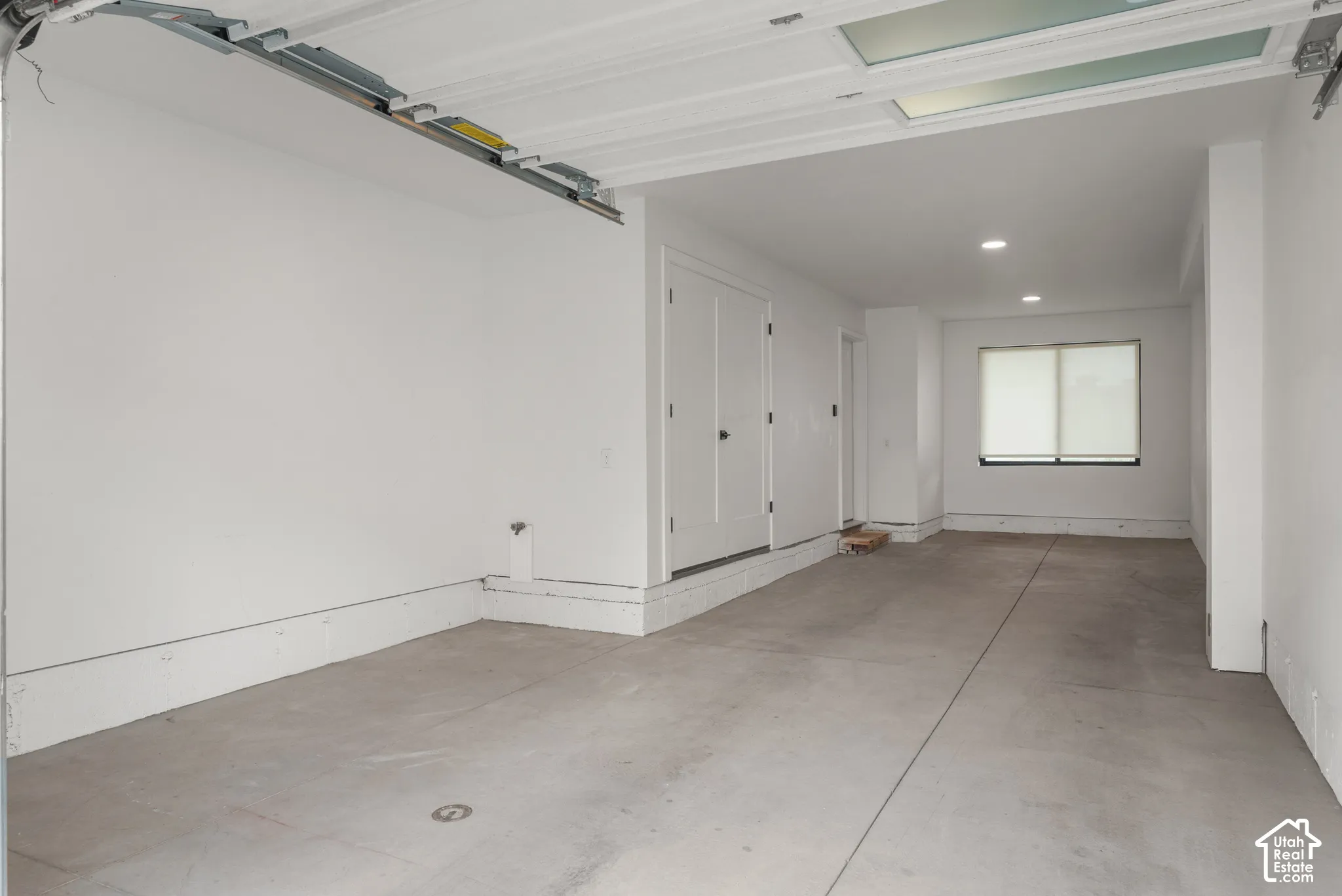 Garage featuring concrete flooring, crisp white walls, recessed ceiling lighting, and a dual-panel door