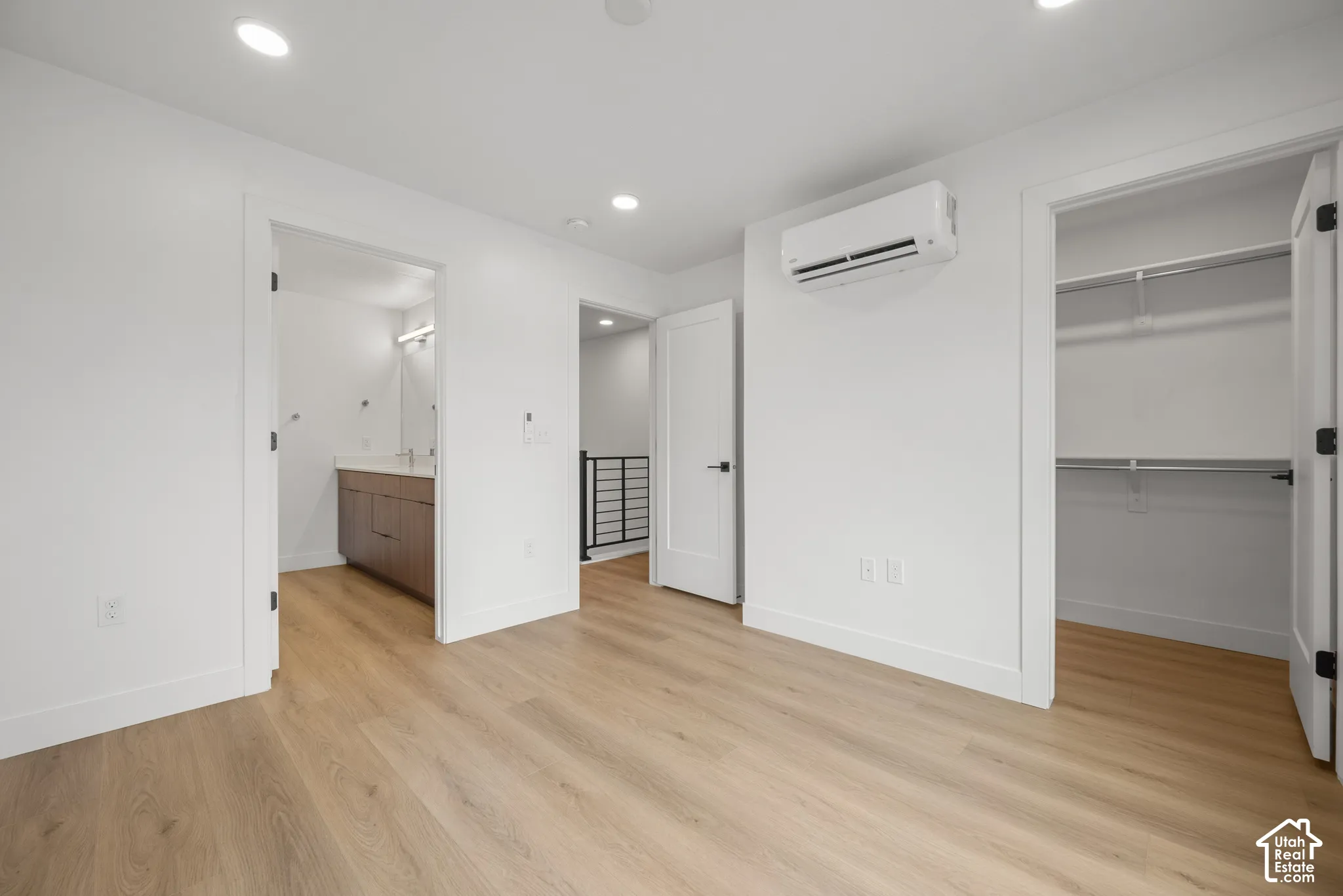 Wood-finish flooring, recessed lighting, wall-mounted climate control unit, walk-in closet with built-in shelving, and shaker-style interior doors