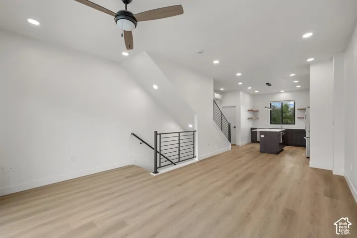 Open-concept interior featuring wood-finish flooring, recessed lighting, a ceiling fan, and metal stair railings