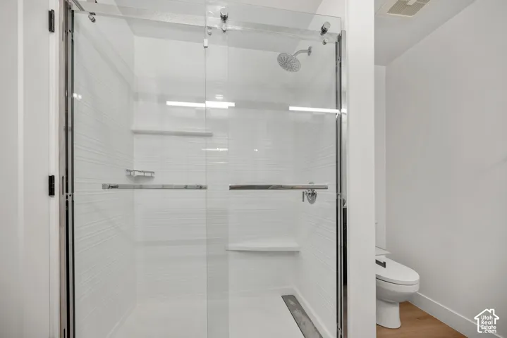 Walk-in shower featuring a sliding frameless glass door, textured horizontal tile surround, built-in shelving, chrome rainfall showerhead, and a fixed shower seat