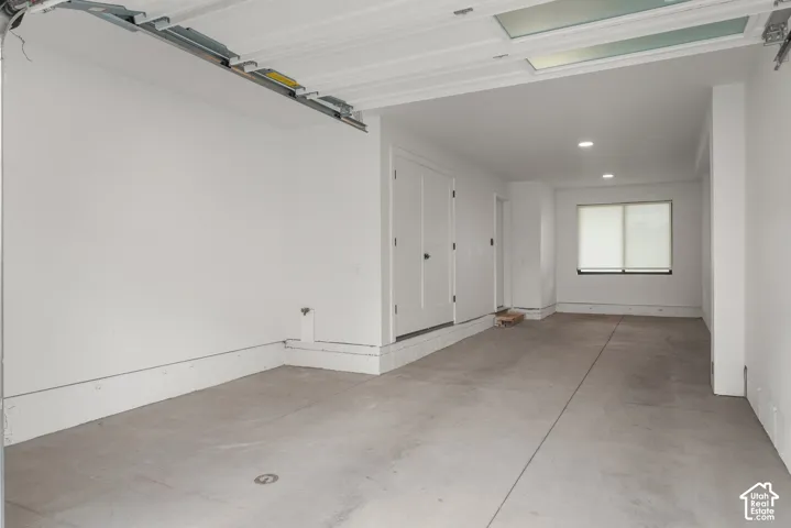 Garage featuring concrete flooring, crisp white walls, recessed ceiling lighting, and a dual-panel door