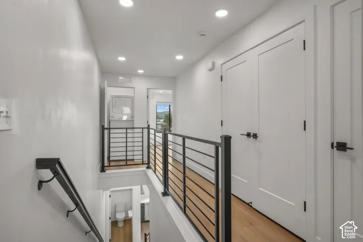 Hallway featuring wood-finish flooring, matte black metal railings, recessed lighting, and dual-panel interior doors with matte black hardware