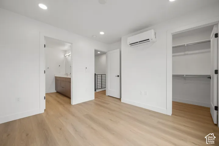 Wood-finish flooring, recessed lighting, wall-mounted climate control unit, walk-in closet with built-in shelving, and shaker-style interior doors