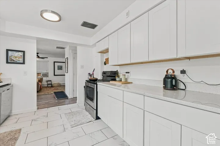 Kitchen featuring white shaker-style cabinetry, quartz countertops, stainless steel appliances, and large-format tile flooring