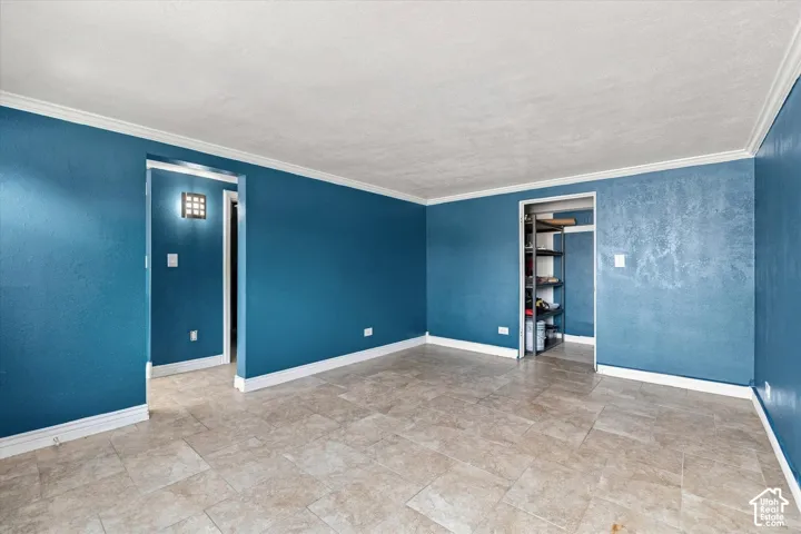 Interior room featuring large-format ceramic tile flooring, textured wall surfaces, and a square-grid wall-mounted light fixture