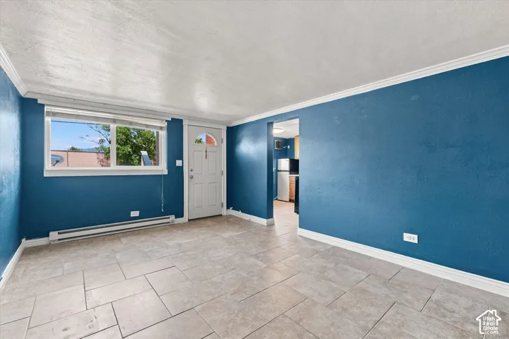 Large-format tile flooring, textured walls, crown molding, and an exterior door with a glass insert