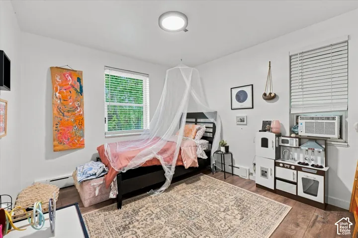 Room featuring wood-finish flooring, two windows with horizontal blinds, and a circular flush-mount ceiling light fixture