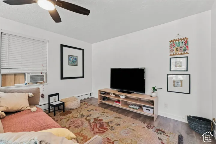 Neutral interior space featuring wood-finish flooring, white walls, and a ceiling-mounted light fixture with fan blades