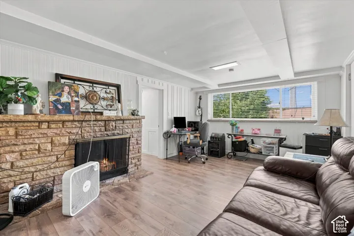 Living area featuring wood-finish flooring, a floor-to-ceiling stone fireplace with a stone hearth, and vertical wood paneling