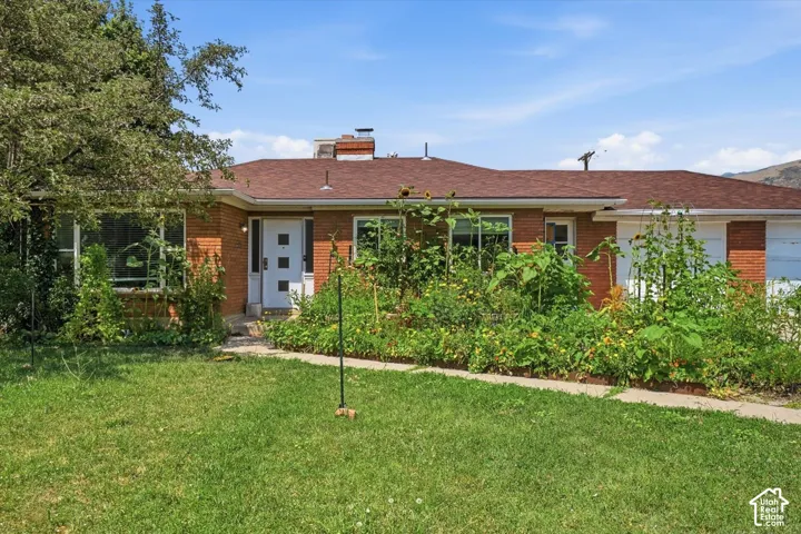 Single-story brick exterior featuring a multi-paneled entry door, asphalt shingle roofing, and an attached two-car garage