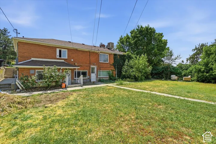 Two-story brick exterior featuring a concrete patio, concrete pathways, and mature landscaping