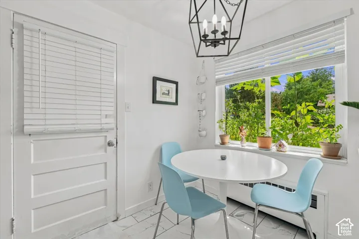 Polished white tile flooring, large multi-pane window, geometric metal pendant lighting, and a solid-core panel door