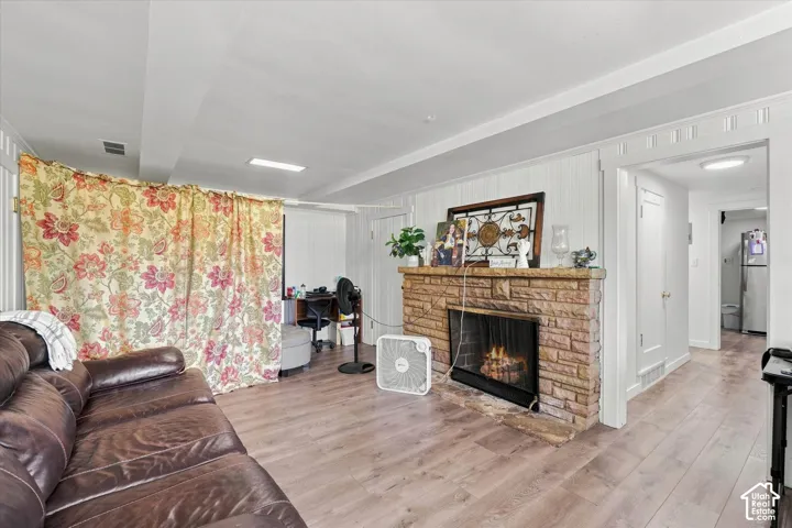 Stone fireplace with a flush-mount insert, wood-finish flooring, and white vertical paneled wall detailing