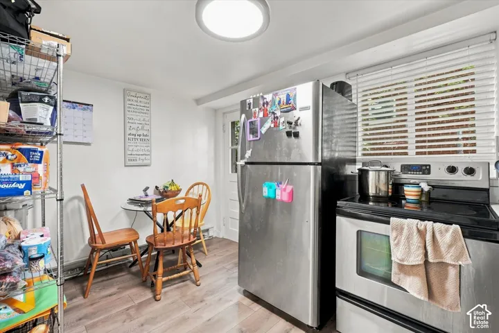 Stainless steel refrigerator and range, wood-finish flooring, flush-mount ceiling lighting, and window with horizontal blinds