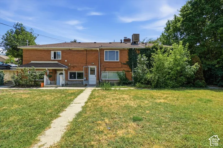 Two-story brick exterior featuring a shingle roof, concrete walkway, and multiple window placements
