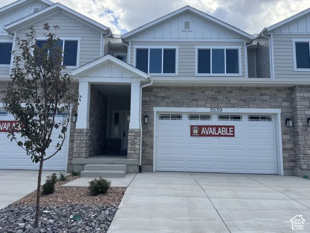 Multi-level exterior featuring horizontal siding, stone veneer accents, two-car garage, and a covered entryway