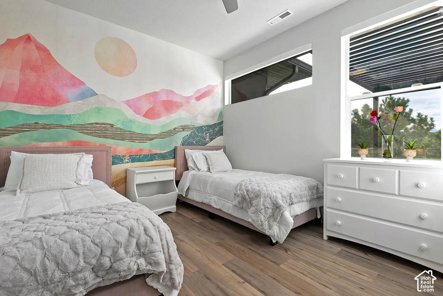 Room featuring wood-finish flooring, a large-scale mural, horizontal clerestory window, and a vertical rectangular window