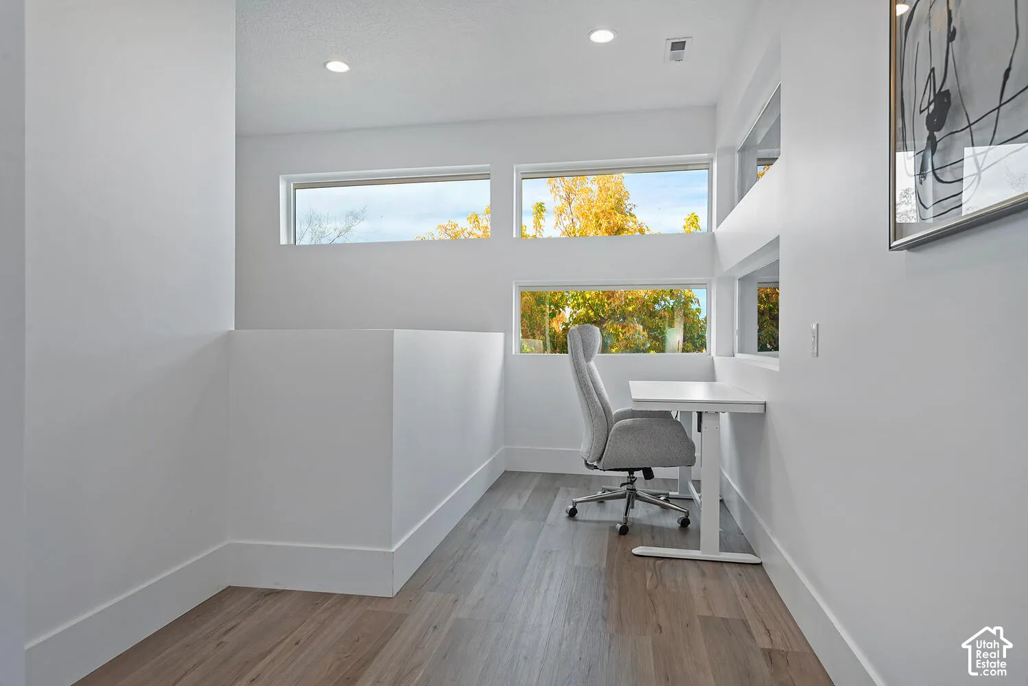 Wood-finish flooring, recessed lighting, and multiple horizontal windows providing natural light
