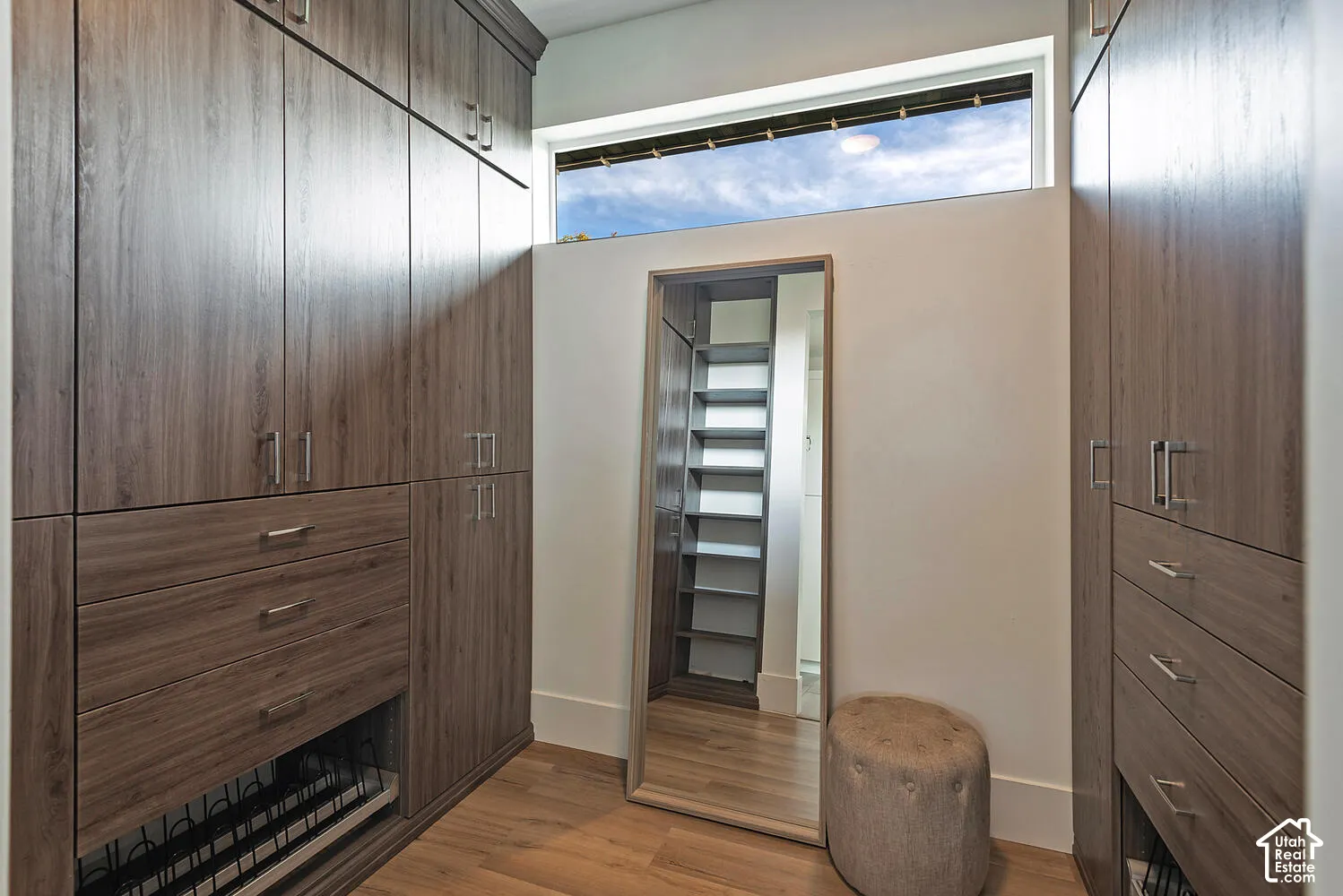 Custom wood-finish cabinetry featuring integrated drawers, open shelving, metallic hardware, and a high-set horizontal window