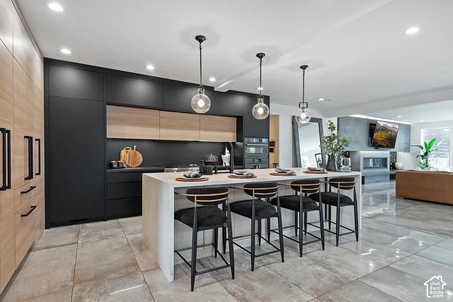 Kitchen featuring custom flat-panel cabinetry, waterfall-edge island, tile flooring, built-in wall oven, and pendant lighting