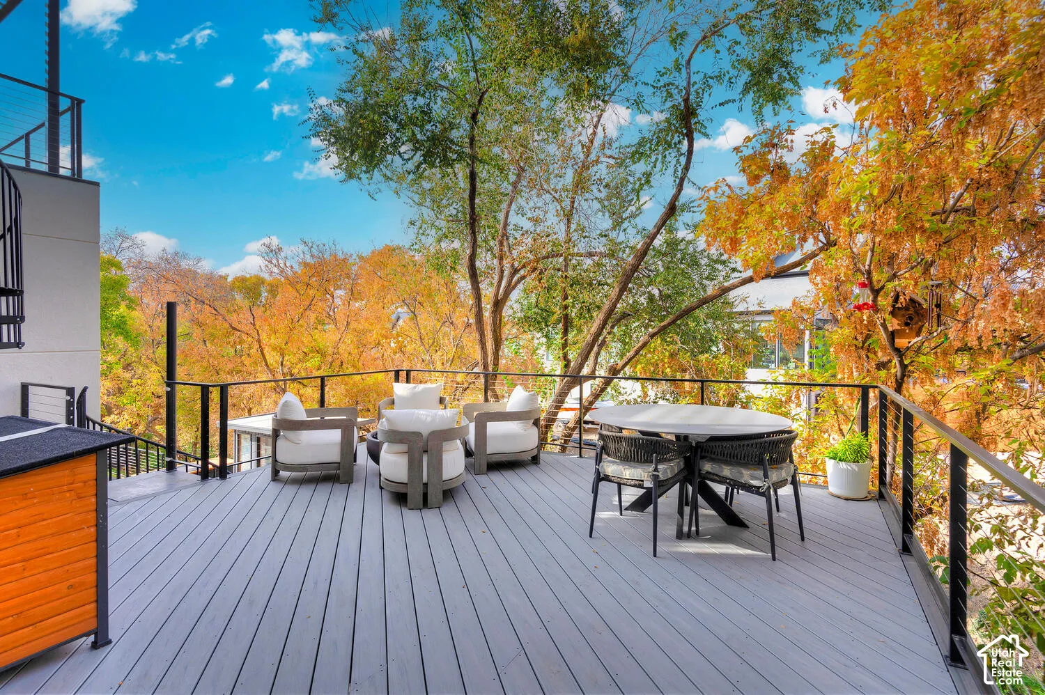 Elevated deck featuring composite decking, black metal railings with horizontal cable infill, and mature surrounding trees