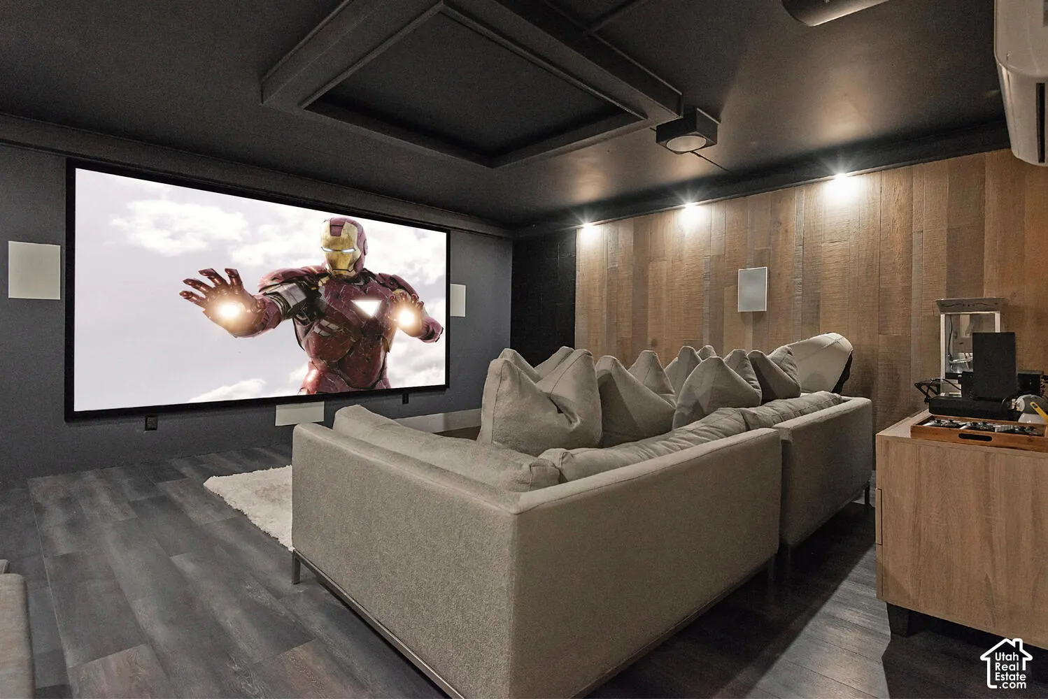 Dedicated media room featuring a large-format projection screen, sound-dampening wall panels, integrated recessed ceiling lighting, and wood-finish flooring
