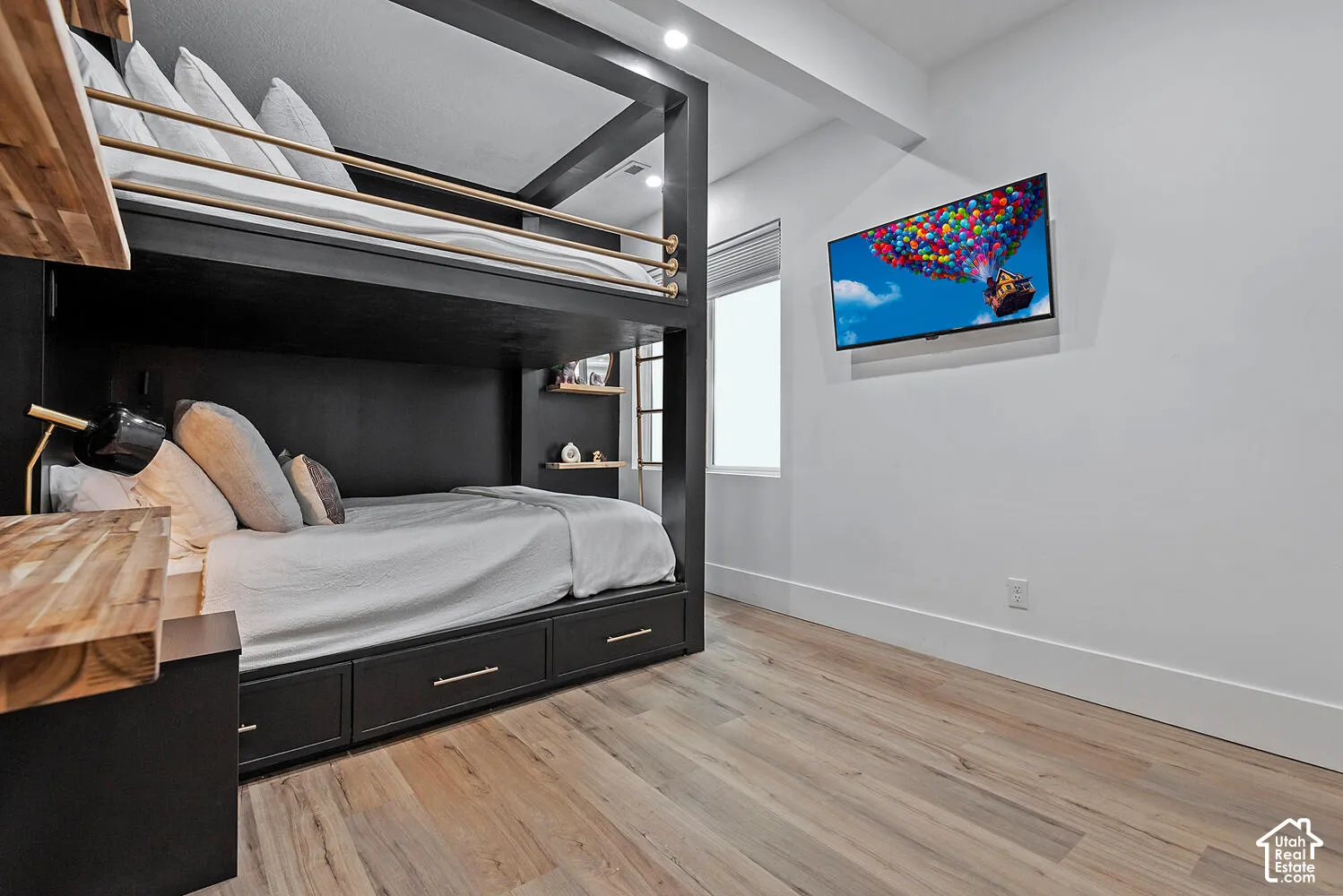 Built-in black wooden bunk bed frame with integrated under-bed storage drawers, natural wood-finish floating shelving, wood-finish desk surface, and wood-finish flooring